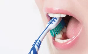 A woman Brushing her teeth.