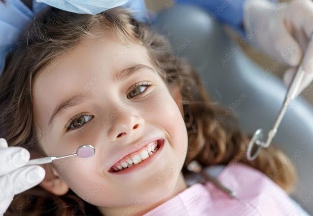 A little girl Smiling during dental treatment.